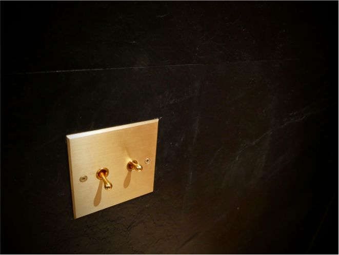 Interrupteur doré sur un mur de salle de bain noir